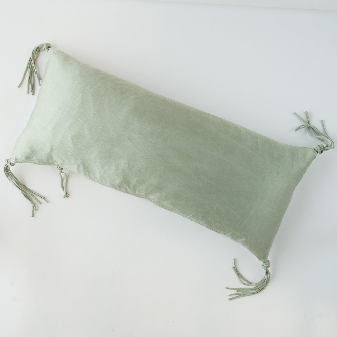 Eucalyptus lumbar pillow with knotted tassel ties at each corner, flat lay view.