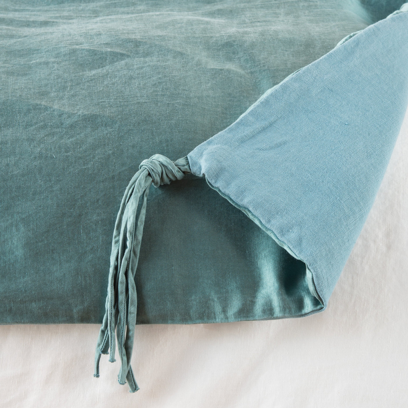 Corner detail of Cenote Taline blanket showing knotted tassel tie closure on folded edge.