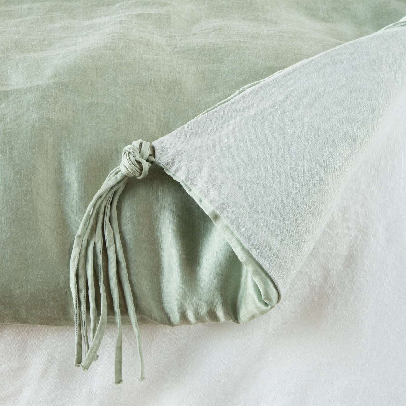 Close-up of Bella Notte Taline blanket corner with knotted fringe tassel detail in Eucalyptus.