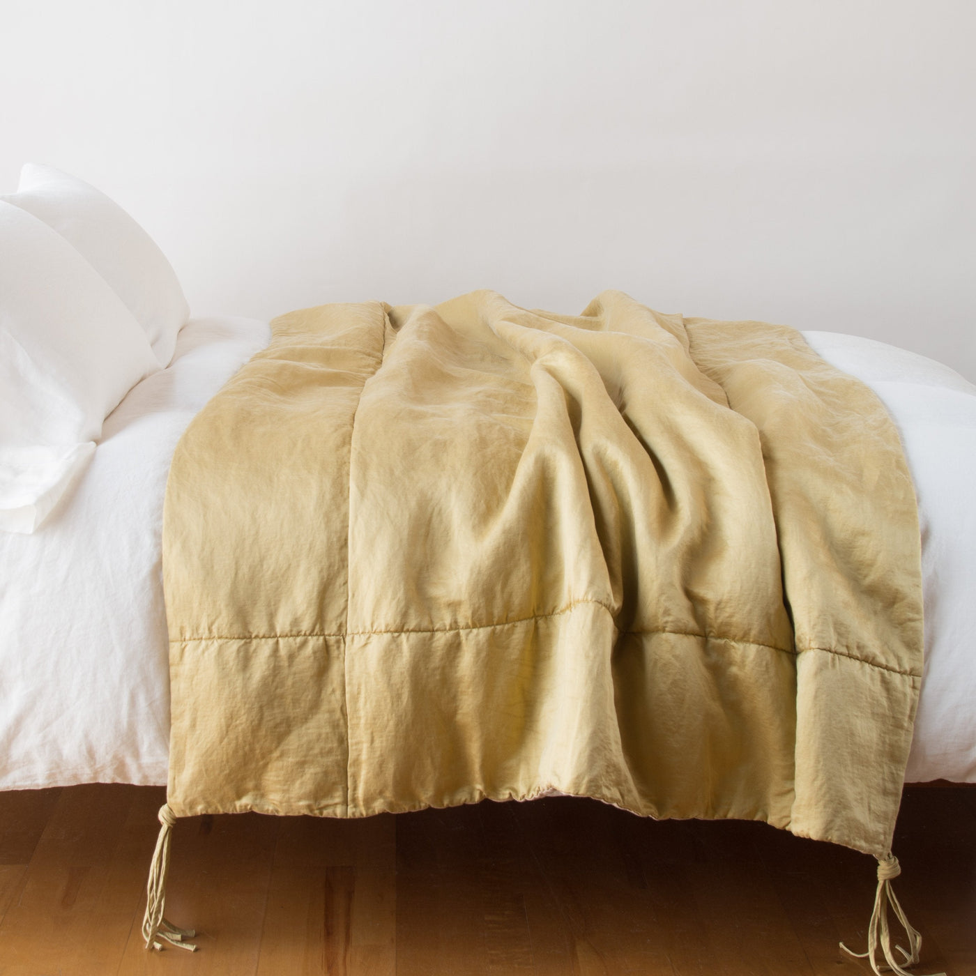 Honeycomb linen throw blanket draped across a white bed, with corner tassel details.