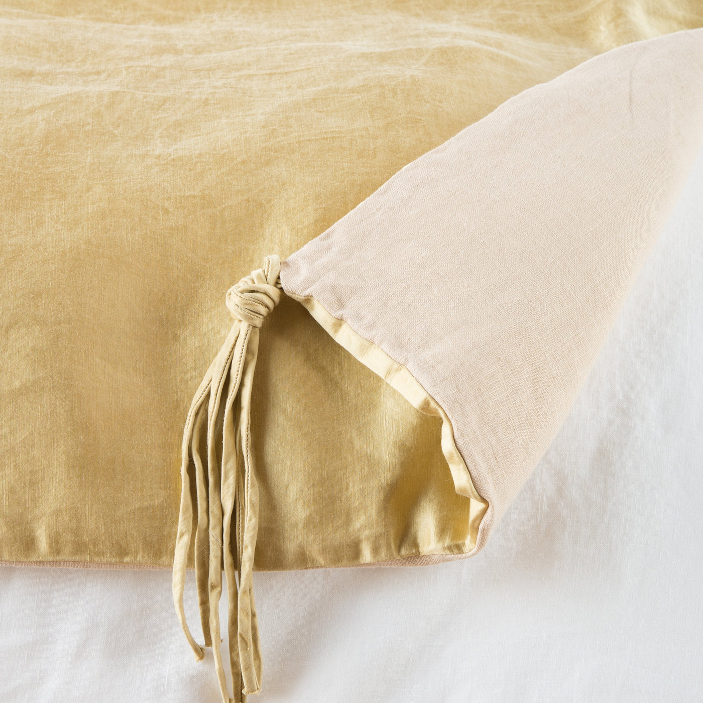 Corner detail of Honeycomb Taline throw blanket showing knotted tassel trim and velvet reverse.