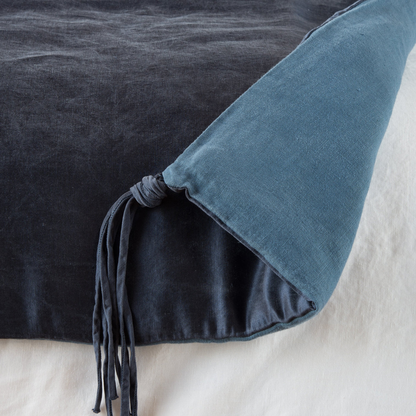 Corner detail of Midnight Taline throw blanket showing tassel tie closure and two-tone linen layers.