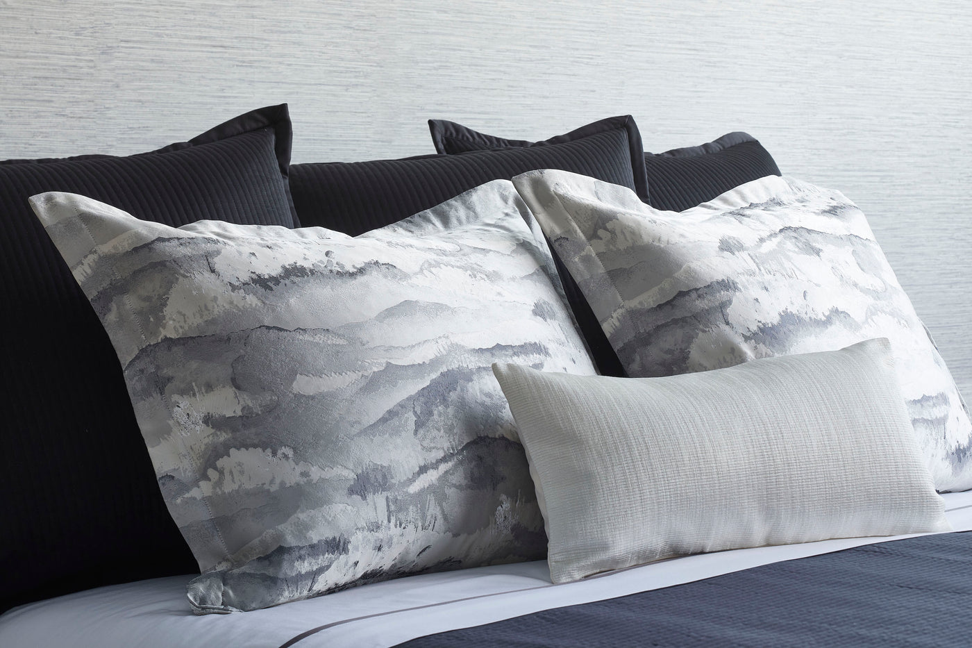 Ann Gish Tempest pillowcases in grey watercolor print styled with charcoal and ivory accent pillows.