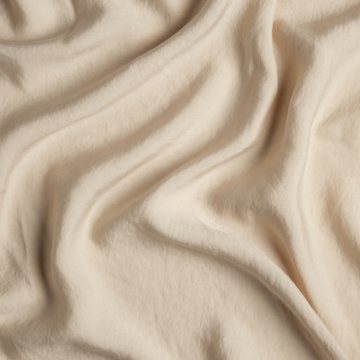 Soft draped folds of Bella Notte Madera Luxe flat sheet in Honeycomb, showing silky fabric sheen.