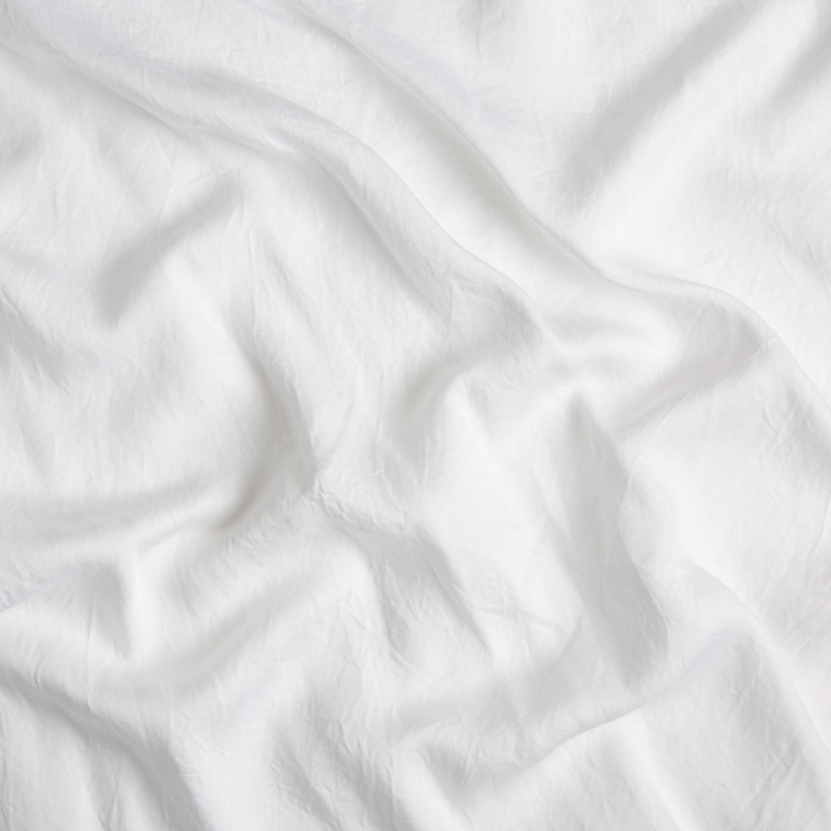 Close-up of draped White Bella Notte Madera Luxe fabric showing soft, fluid texture.