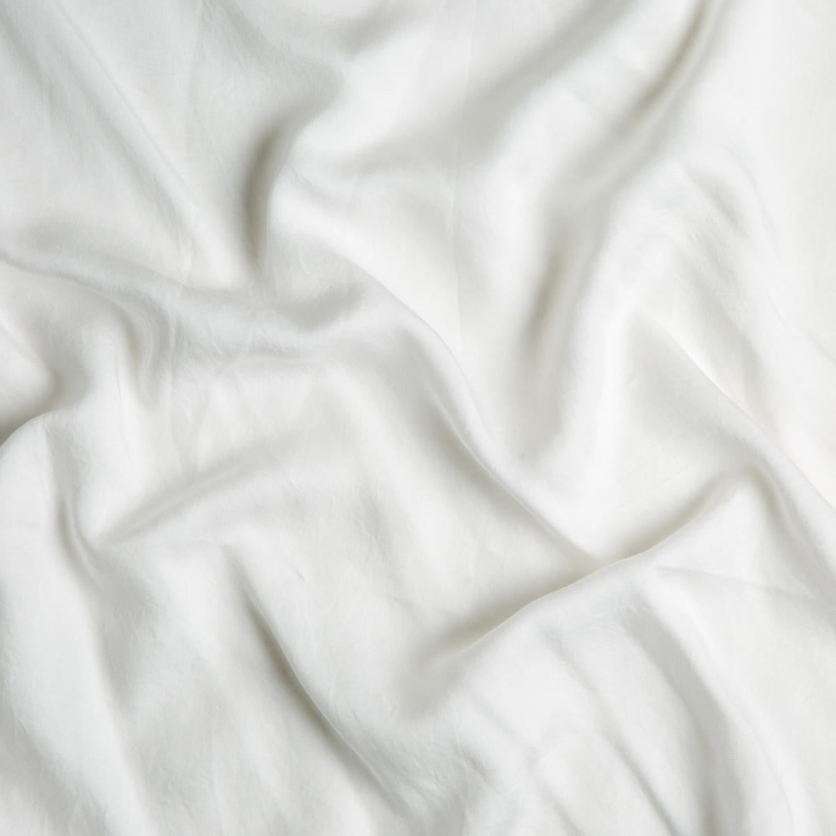 Close-up of Winter White Madera Luxe flat sheet showing soft fabric drape and texture.