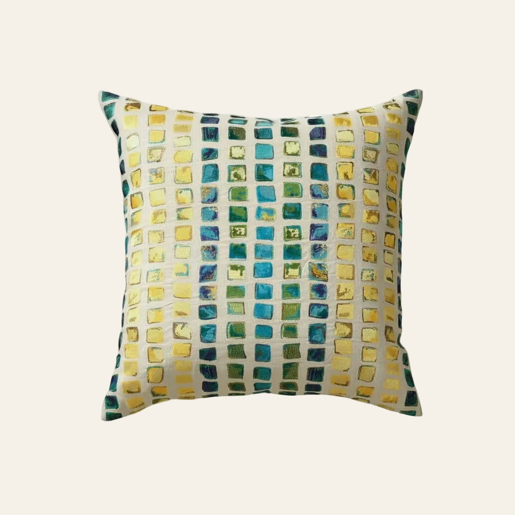 Ann Gish Tesserae Mosaic pillow with teal, gold, and green embroidered square pattern.