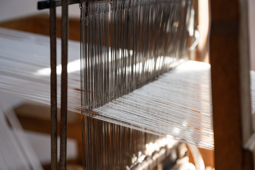 Image of threads passing through heddles on shafts of a loom