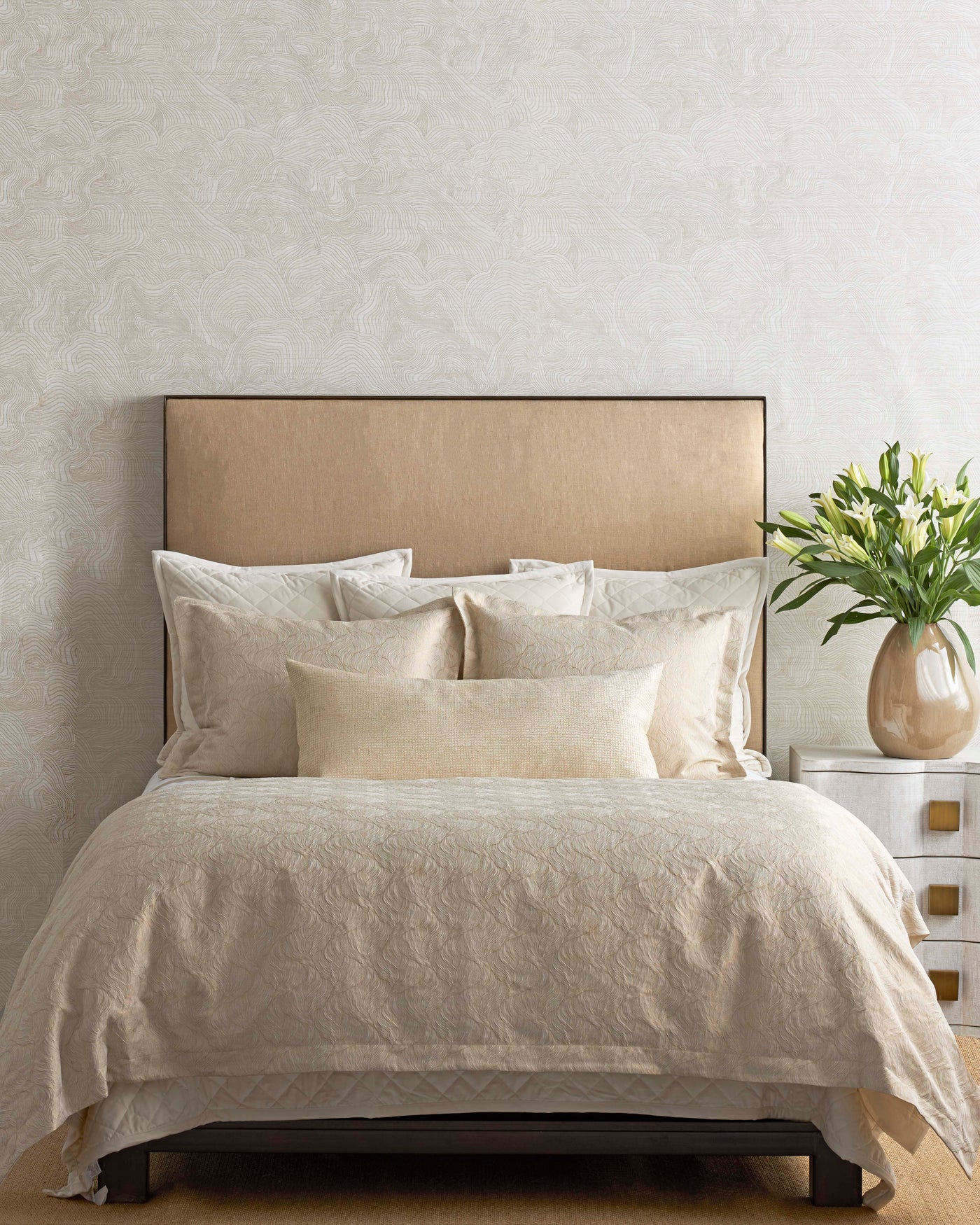 Ivory and champagne duvet set styled on bed with layered pillows and white tulip arrangement.