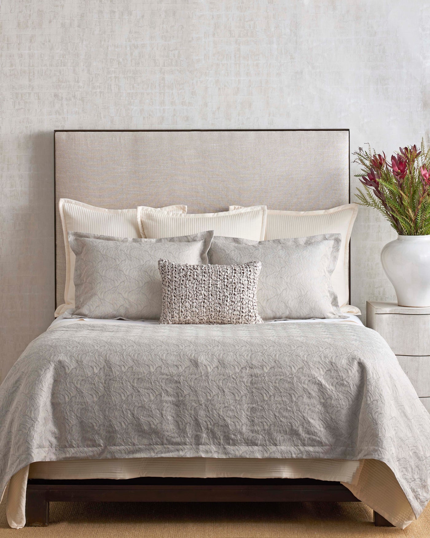Styled bed with Ann Gish Tidal duvet set in silver-grey, layered with ivory and textured accent pillows.