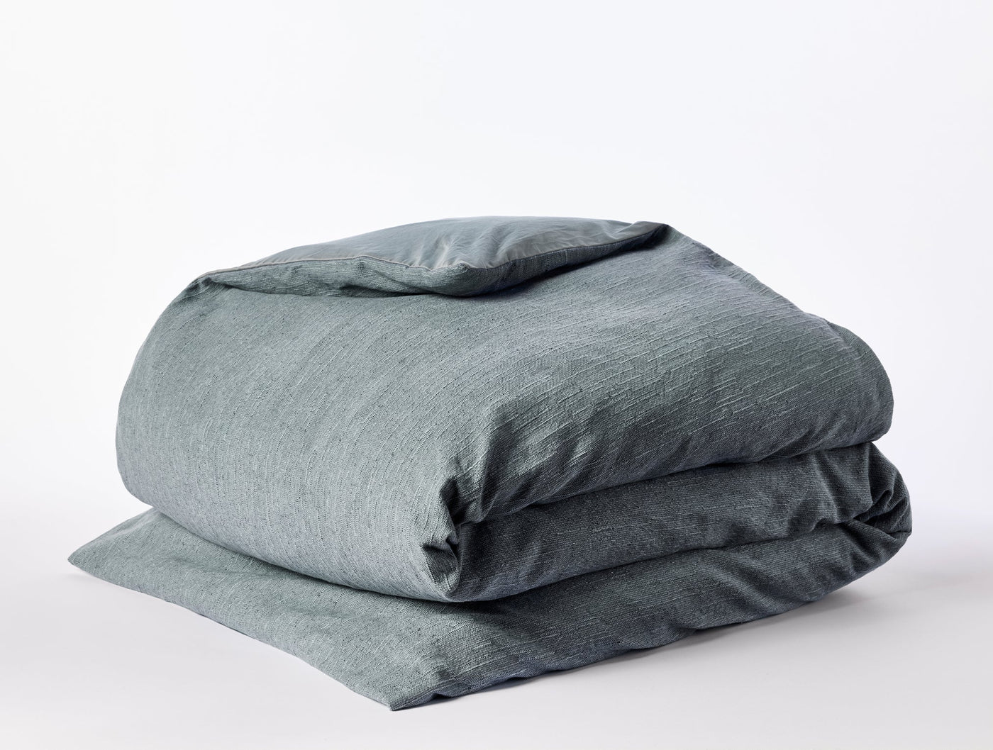Slate blue-green linen duvet cover folded neatly, showing natural heathered texture.