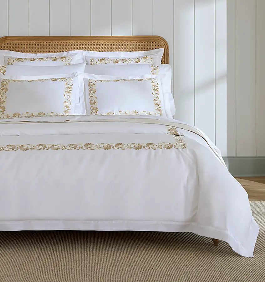 White Sferra Tralcio duvet cover with champagne floral embroidered border on styled bed.