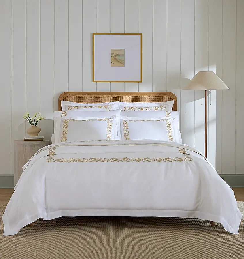 White Sferra Tralcio duvet cover with gold floral embroidered border on styled bed.
