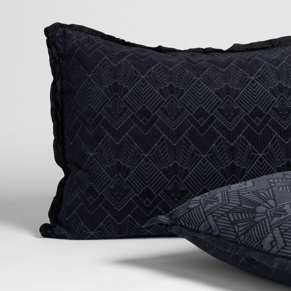 Close-up of Bella Notte Trettino sham in Slate, showing geometric jacquard pattern and flanged edge.