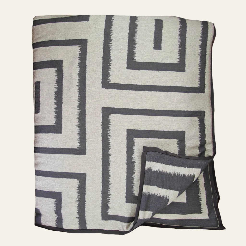 Ann Gish Unmazed throw in ivory and charcoal geometric ikat maze pattern, folded.
