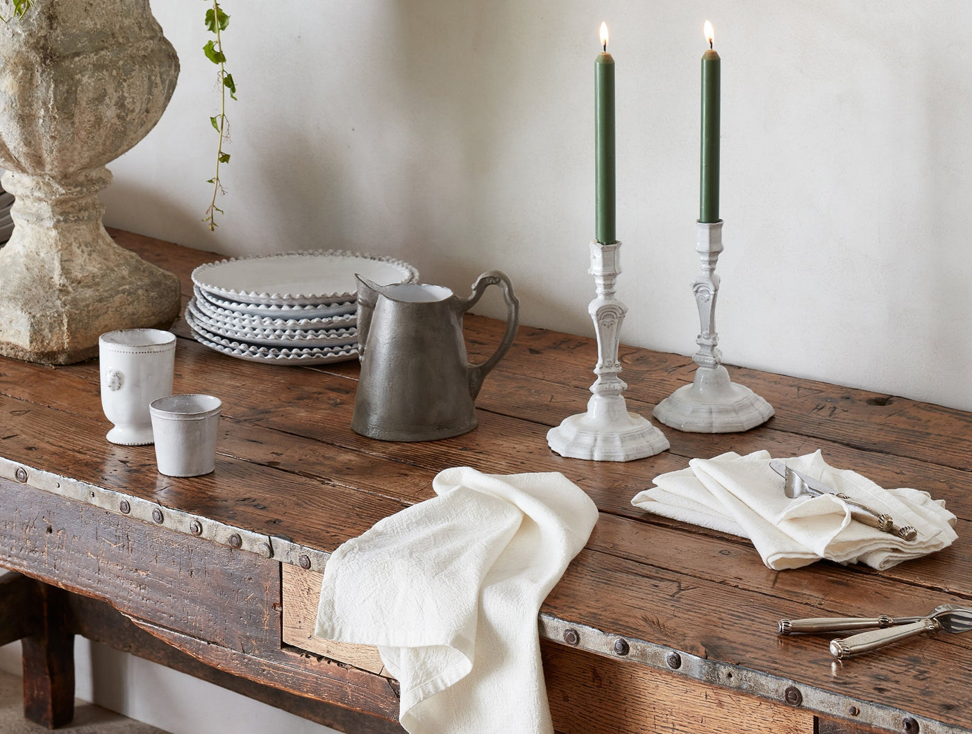 Ivory linen napkins styled on a rustic wood table with candlesticks and ceramic plates.