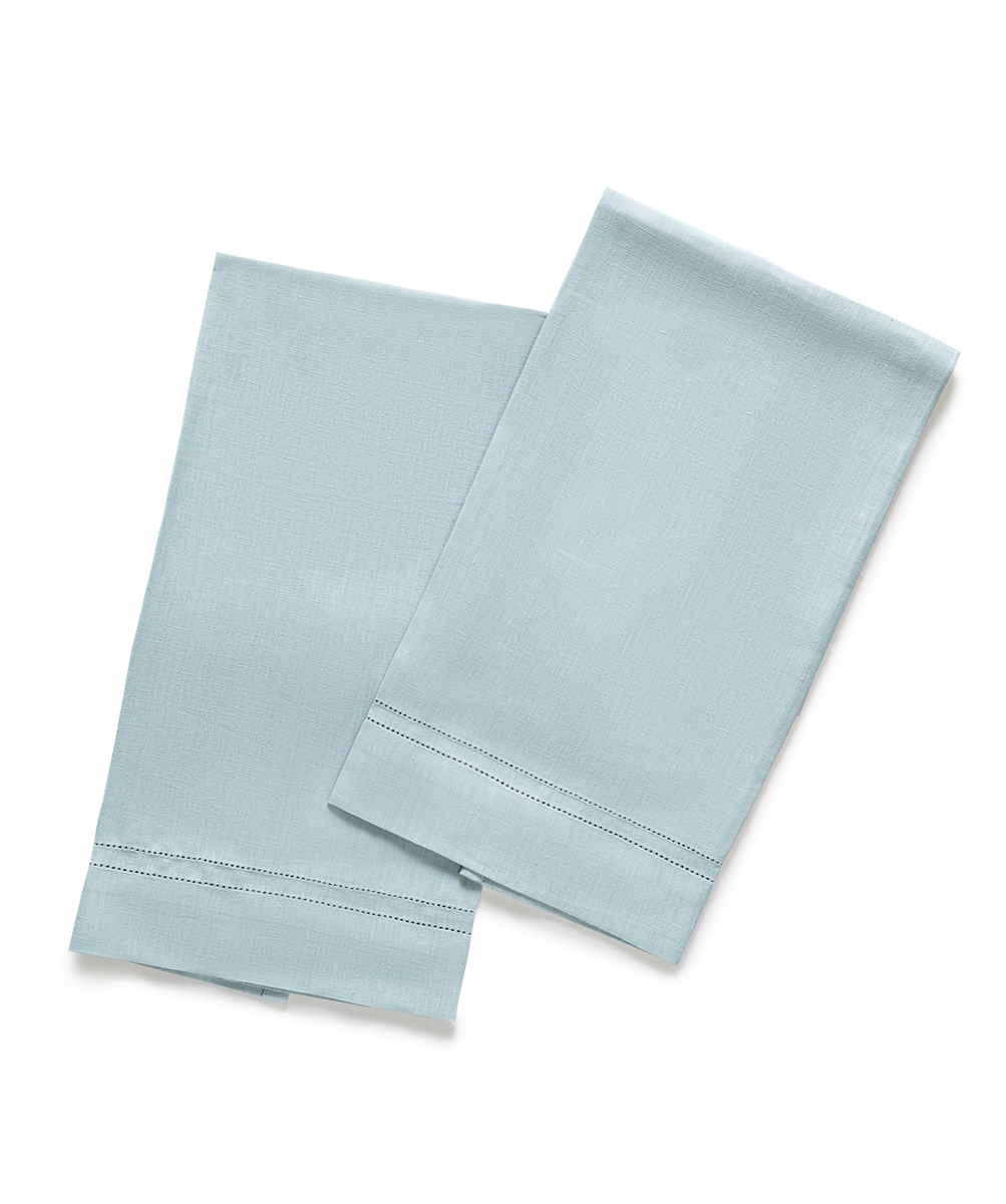 Two Valentina Hemstitch Guest Towels by Matouk in light blue, featuring a hemstitch border, are neatly folded and overlapping on a plain white background—ideal for elevating any luxurious tabletop collection.