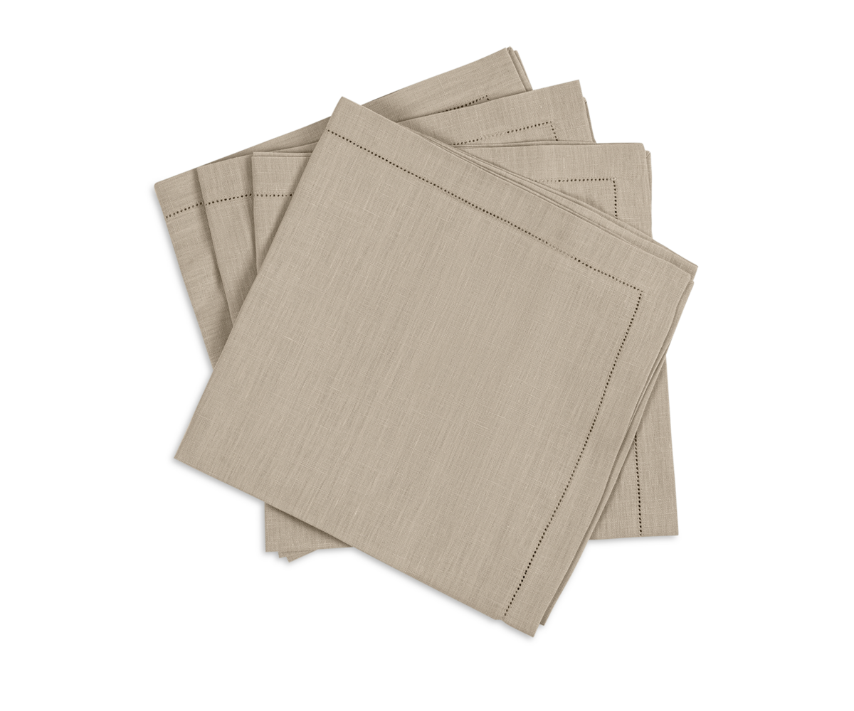 The Valentina Hemstitch Napkin Set by Matouk features four neatly folded beige napkins with a hemstitch border, stacked on a white background—an elegant upgrade to any tabletop collection.