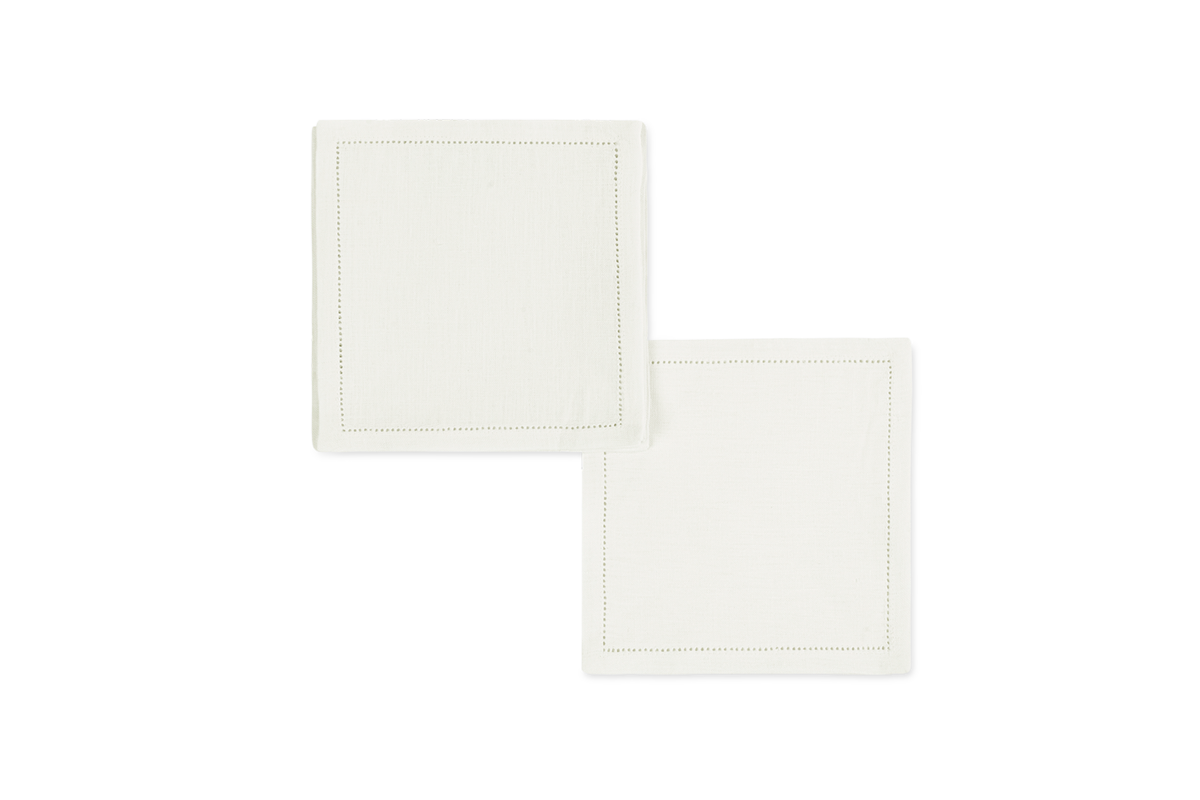 The Valentina Hemstitch Cocktail Napkin Set by Matouk features two white linen napkins with a subtle hemstitch border, displayed on a white background—a timeless touch for any elegant table.