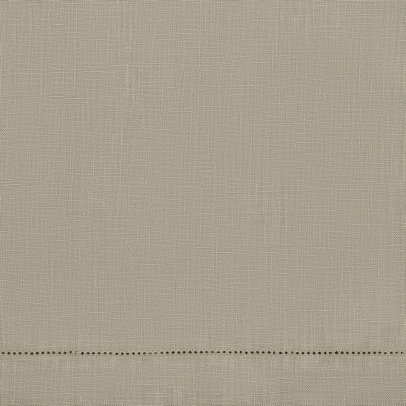 The Matouk Valentina Hemstitch Tablecloth features beige textured fabric with a classic hemstitch border, visible horizontal hem, and delicate decorative holes near the edge for a timeless, elegant tabletop look.