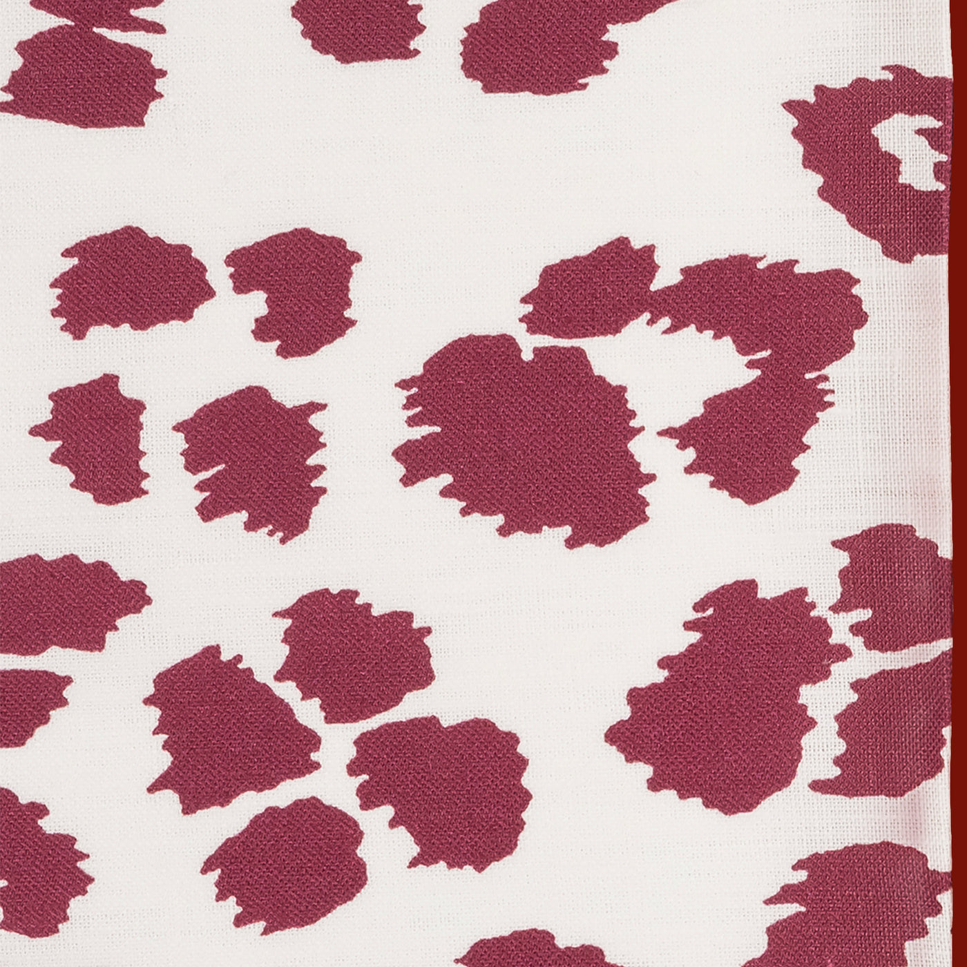 Close-up of raspberry leopard-print woven fabric with ivory ground.