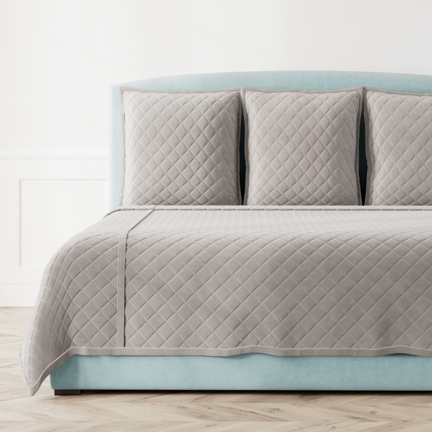 Diamond-quilted silver velvet coverlet set on a styled aqua bed, full view.