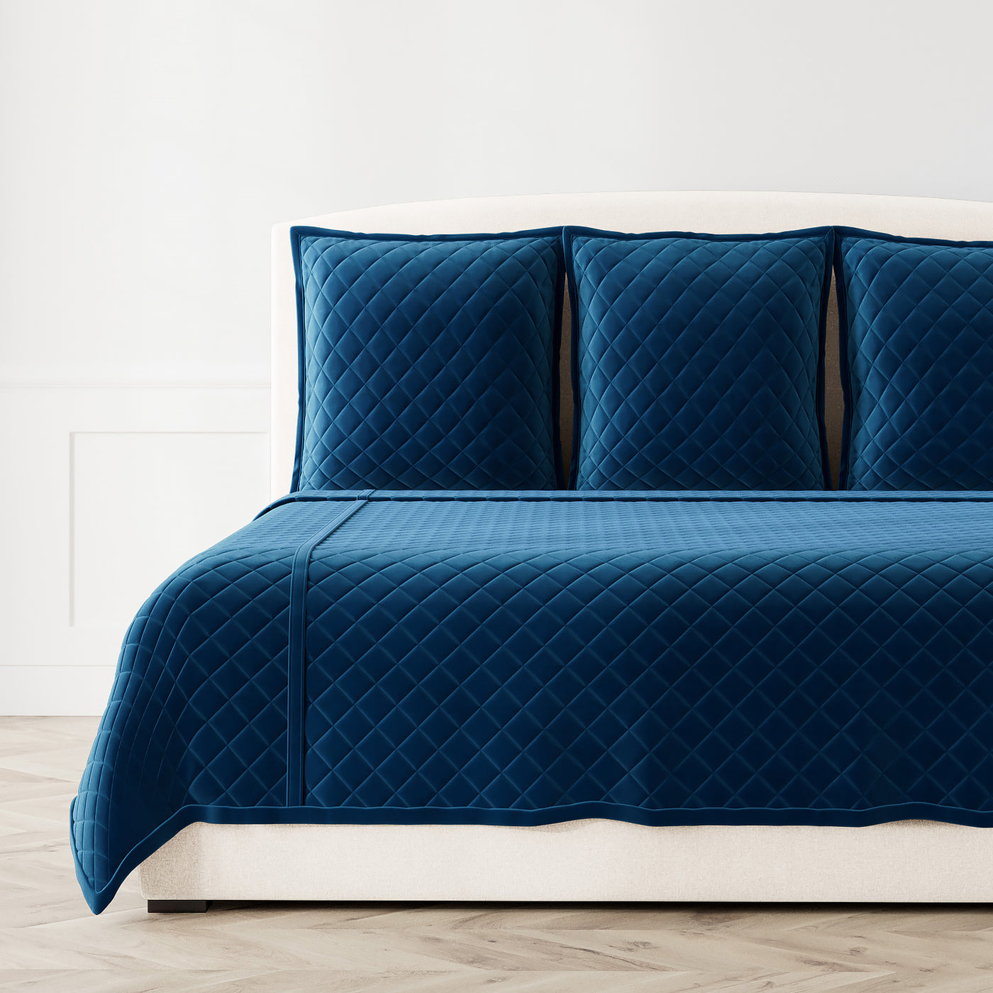 Navy blue velvet coverlet set with diamond quilting, styled on a bed with matching shams.