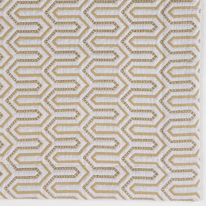 Close-up of Vendome pillow cover fabric showing gold geometric hexagon embroidery on ivory.