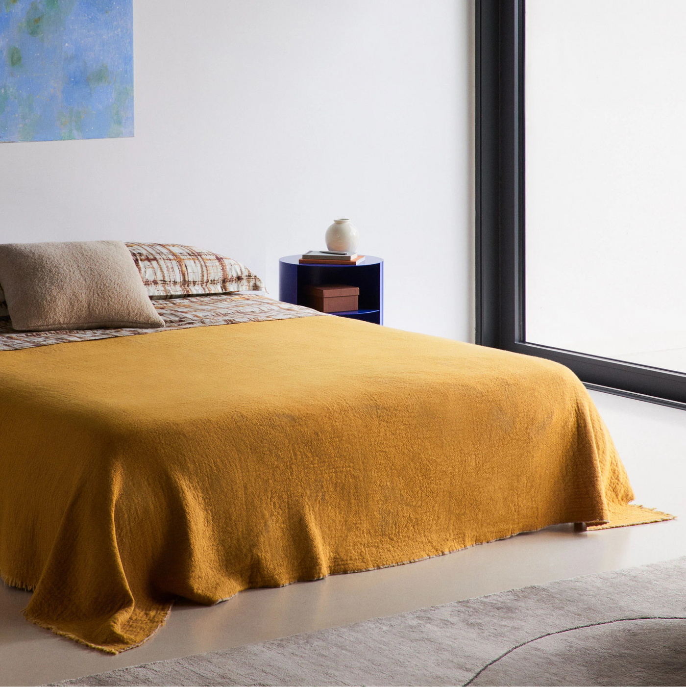 Lanerossi Venere blanket in mustard yellow draped over a styled bed.