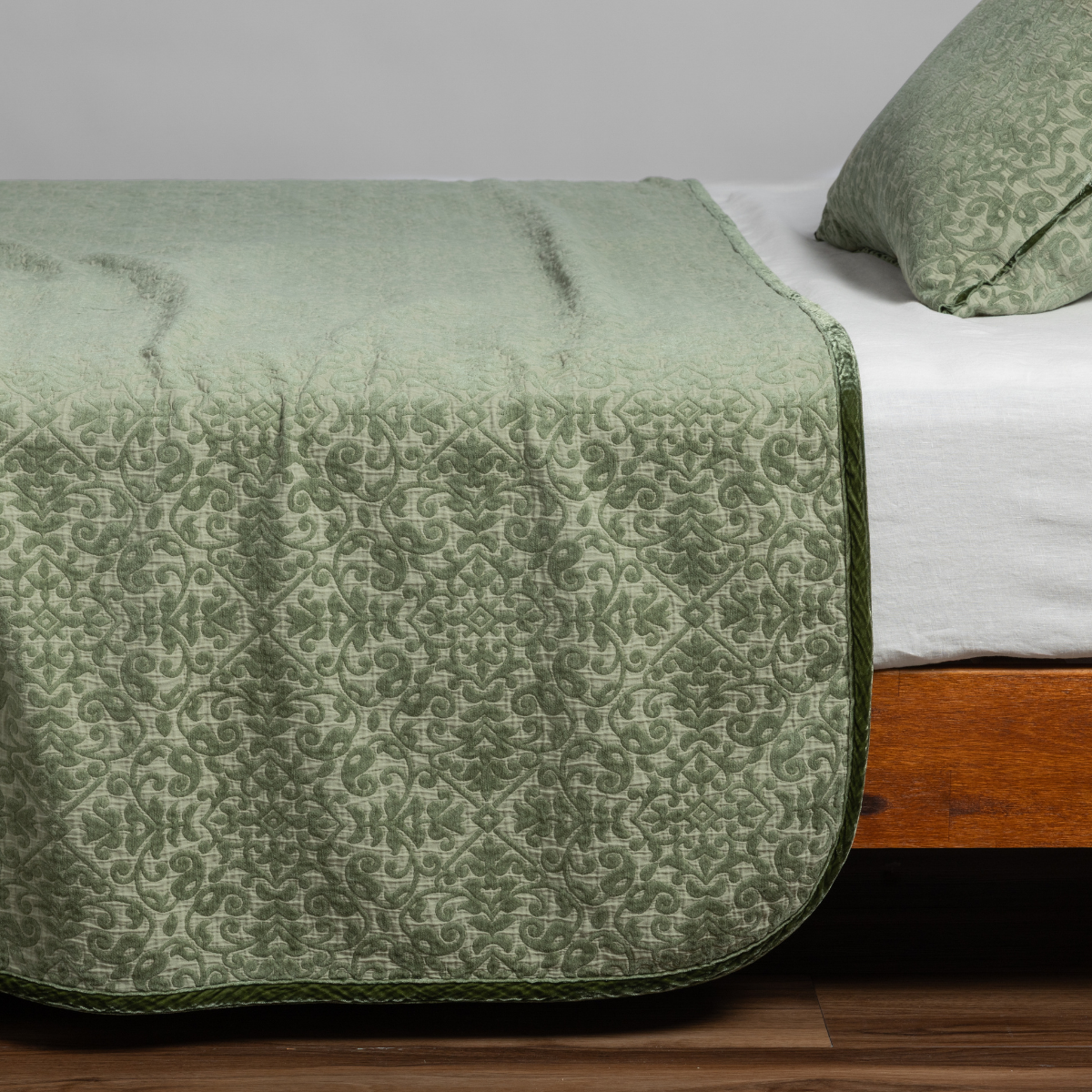 Bella Notte Vienna coverlet in Desert Sage, showing damask pattern draping over bed foot.