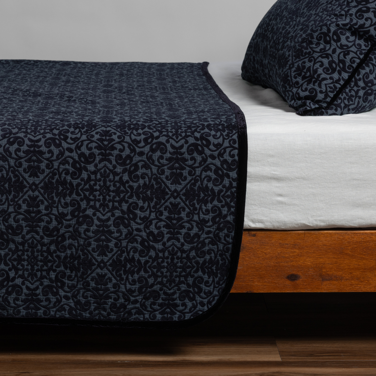 Bella Notte Vienna coverlet in Slate, draped over bed foot showing damask pattern detail.