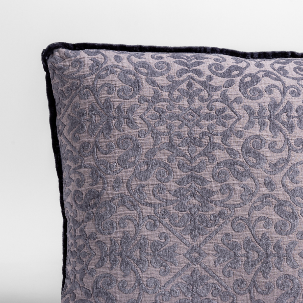 Close-up of French Lavender Vienna sham corner, showing damask quilted texture and dark piped edge.