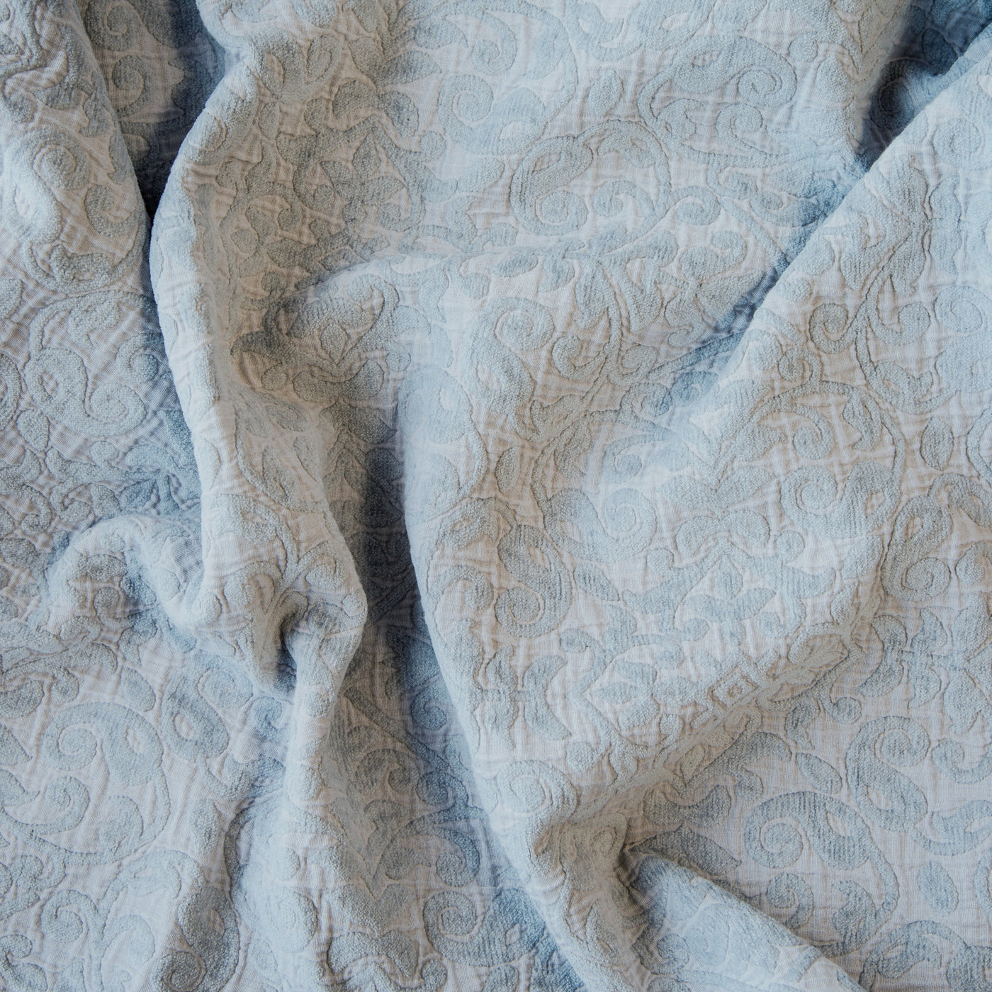 Close-up of Bella Notte Vienna sham in Cloud, showing draped jacquard fabric with tonal floral scroll pattern.