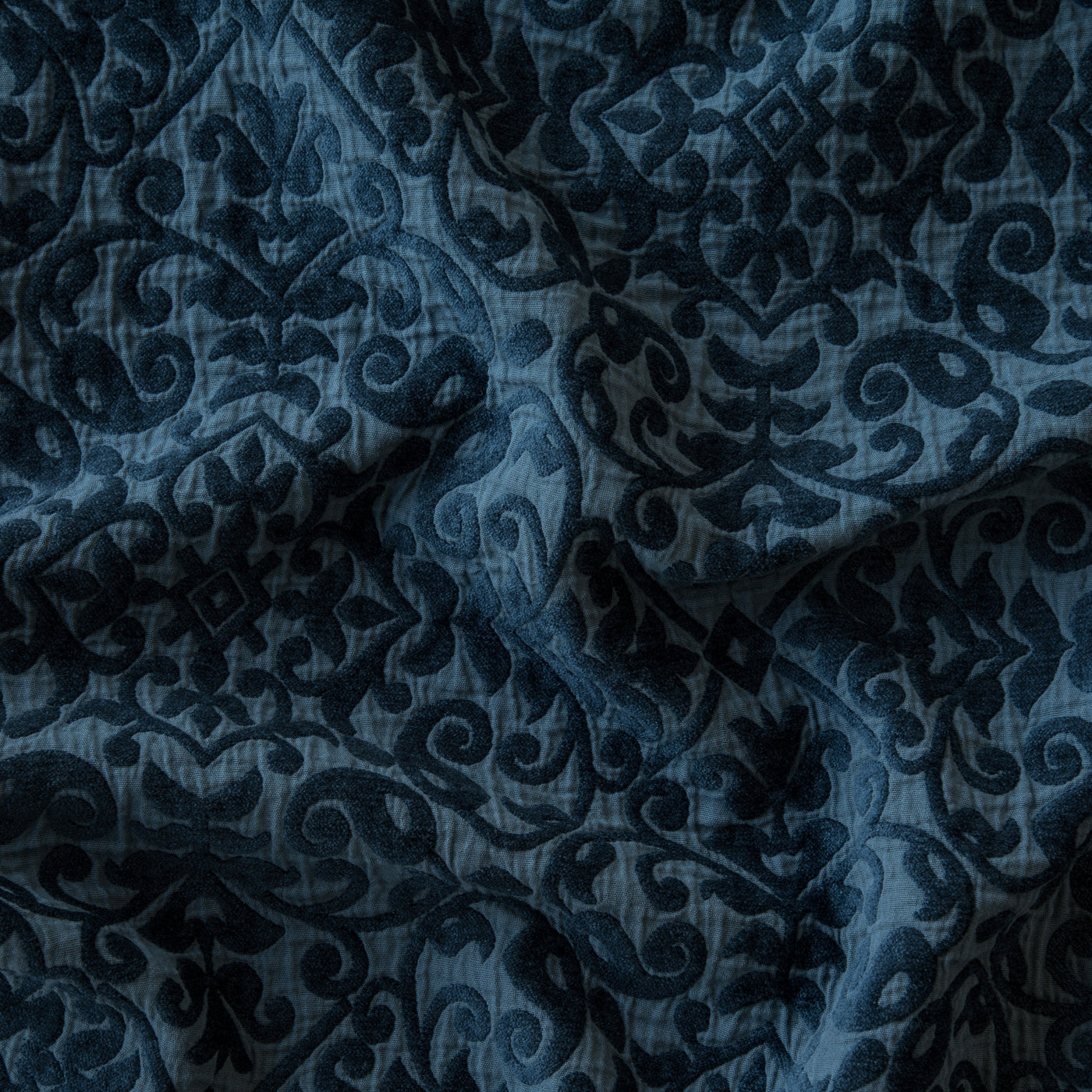 Close-up of Bella Notte Vienna coverlet in Midnight, showing draped damask-patterned fabric.