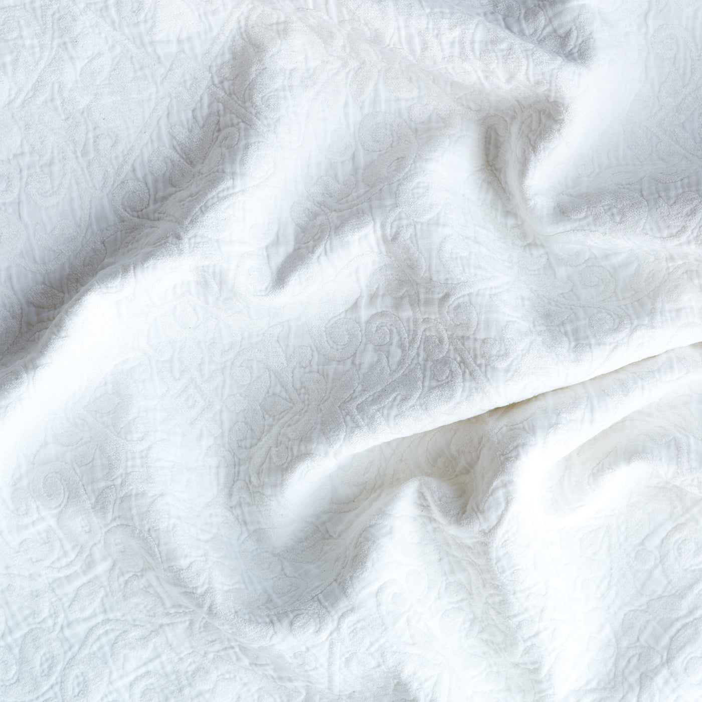 Close-up of Bella Notte Vienna sham in White, showing tone-on-tone jacquard scroll pattern on draped fabric.