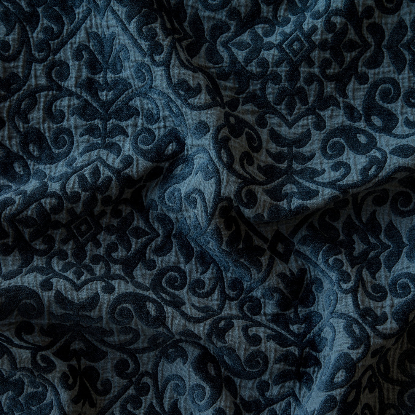 Close-up of Bella Notte Vienna sham in Midnight, showing damask velvet pattern on draped fabric.