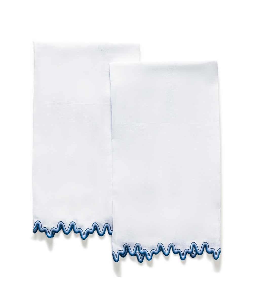 The Wave | Linen Guest Towel Set by Matouk features two white linen guest towels with a wavy blue two-tone border, shown against a plain light background.