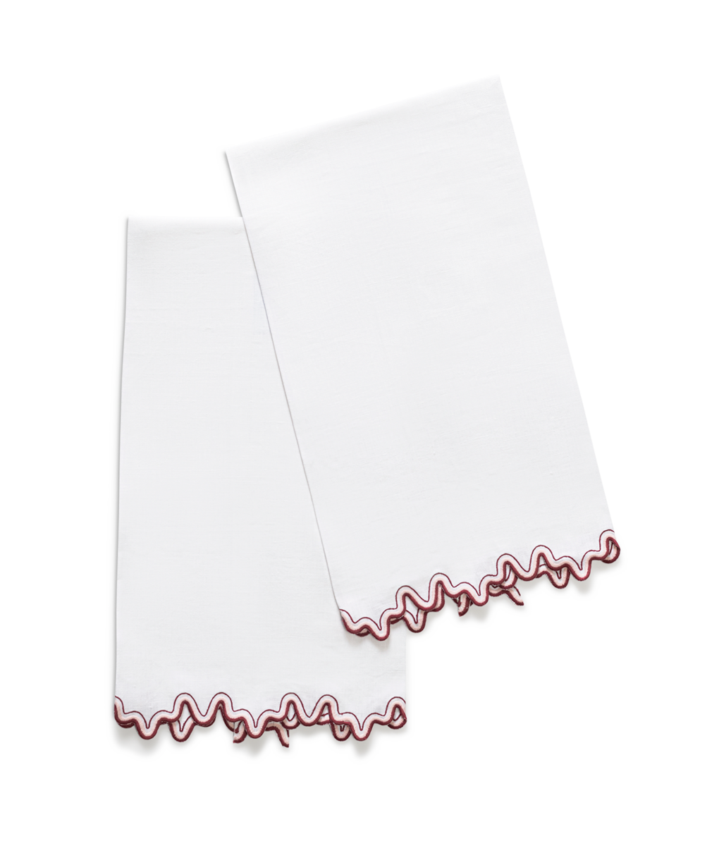 The Wave | Linen Guest Towel Set by Matouk features two white linen towels with wavy red embroidered edges and a two-tone border, displayed side by side to add elegant style to your tabletop decor.