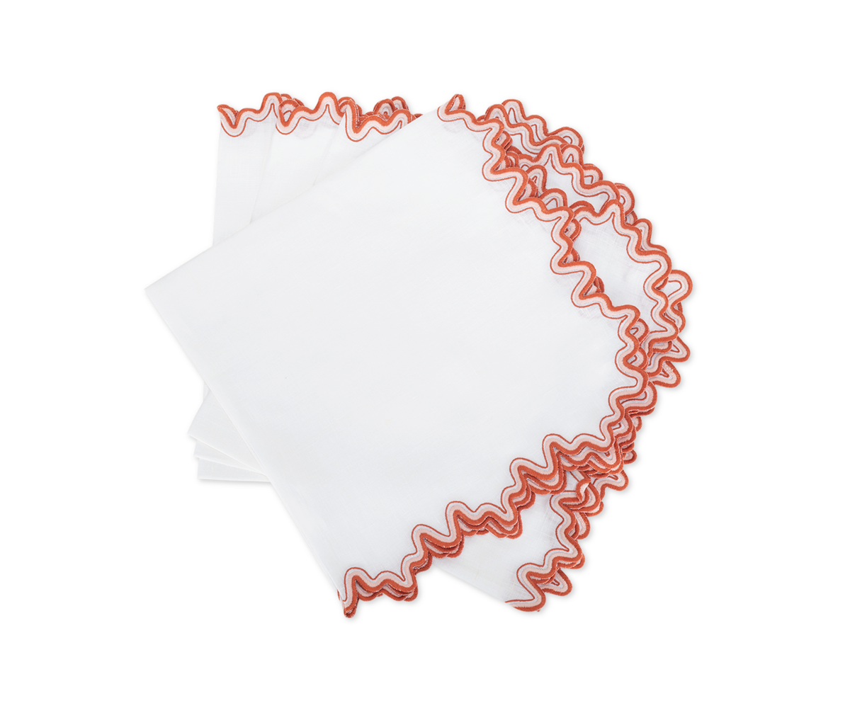 Four luxurious Wave napkins by Matouk with wavy red embroidered edges are neatly stacked on a white background—perfect for adding elegance to your dining space.