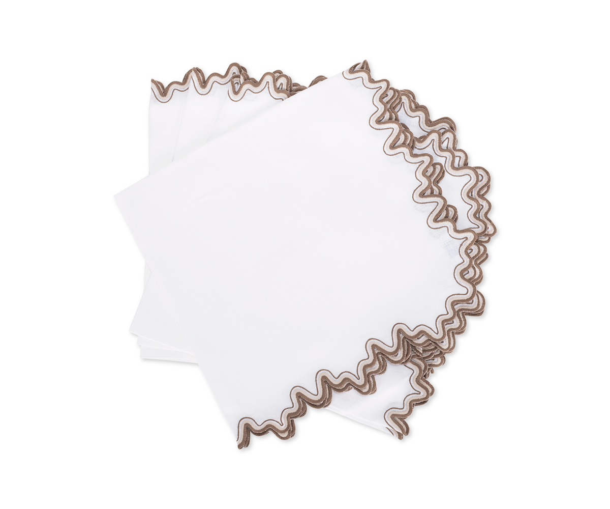 The Wave | Napkin by Matouk features luxurious linen in white with wavy brown embroidered edges—neatly folded and stacked, it's perfect for elevating your dining space.
