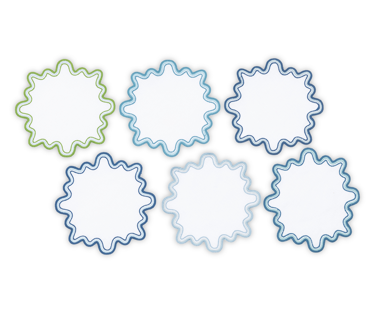 Six circular cocktail napkins from the Matouk Wave set, featuring a luxurious linen look, wavy edges, and two-tone borders—two green, two light blue, and two dark blue—arranged in two rows on a plain white background.