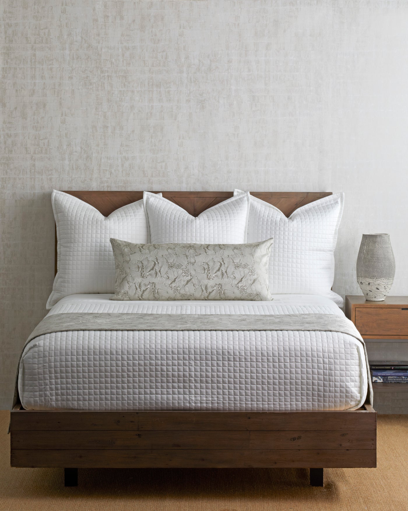 Ann Gish Waves bed finisher styled on a dressed bed with white quilted bedding and a botanical lumbar pillow.