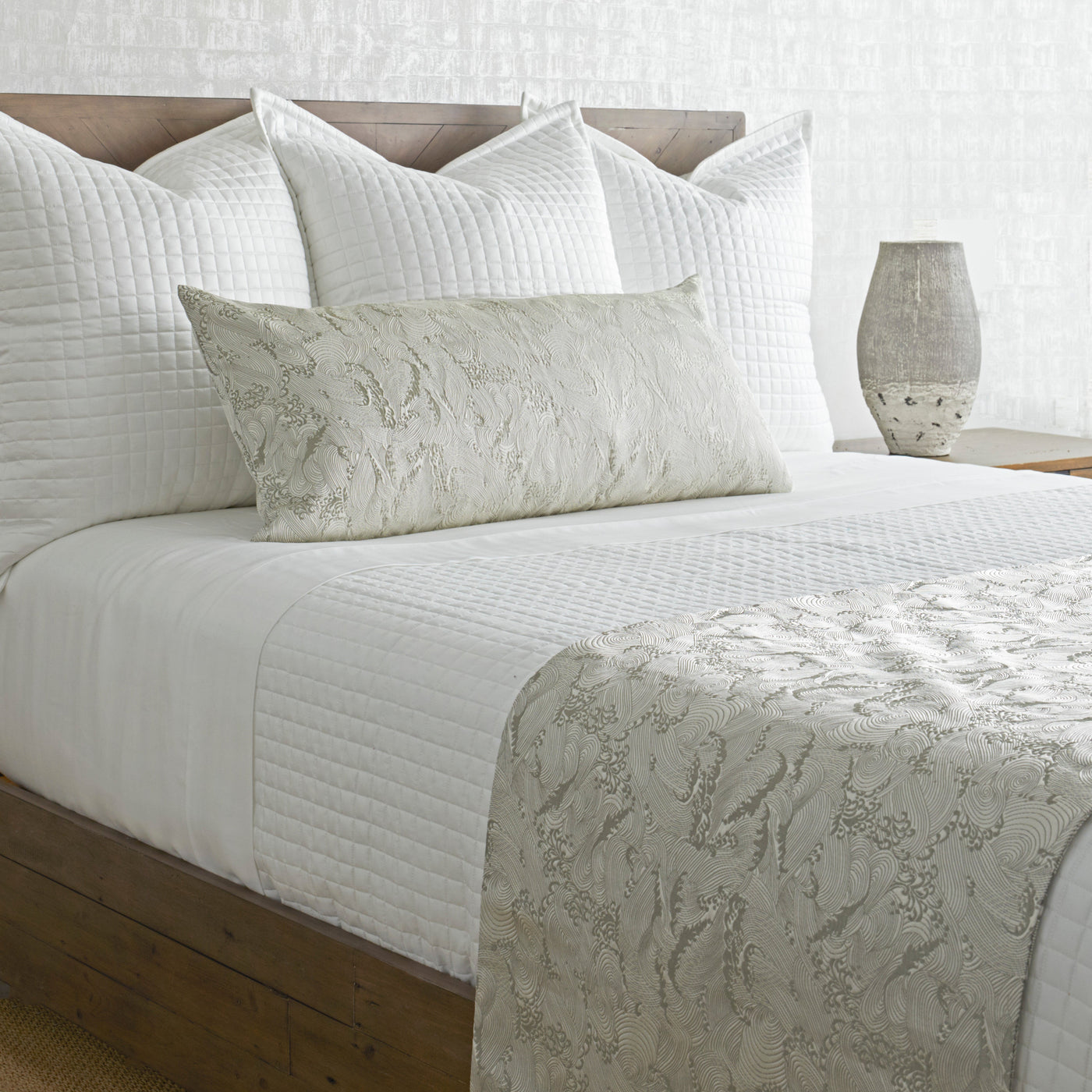 Ann Gish Waves bed finisher in ivory, draped across foot of bed with matching lumbar pillow.