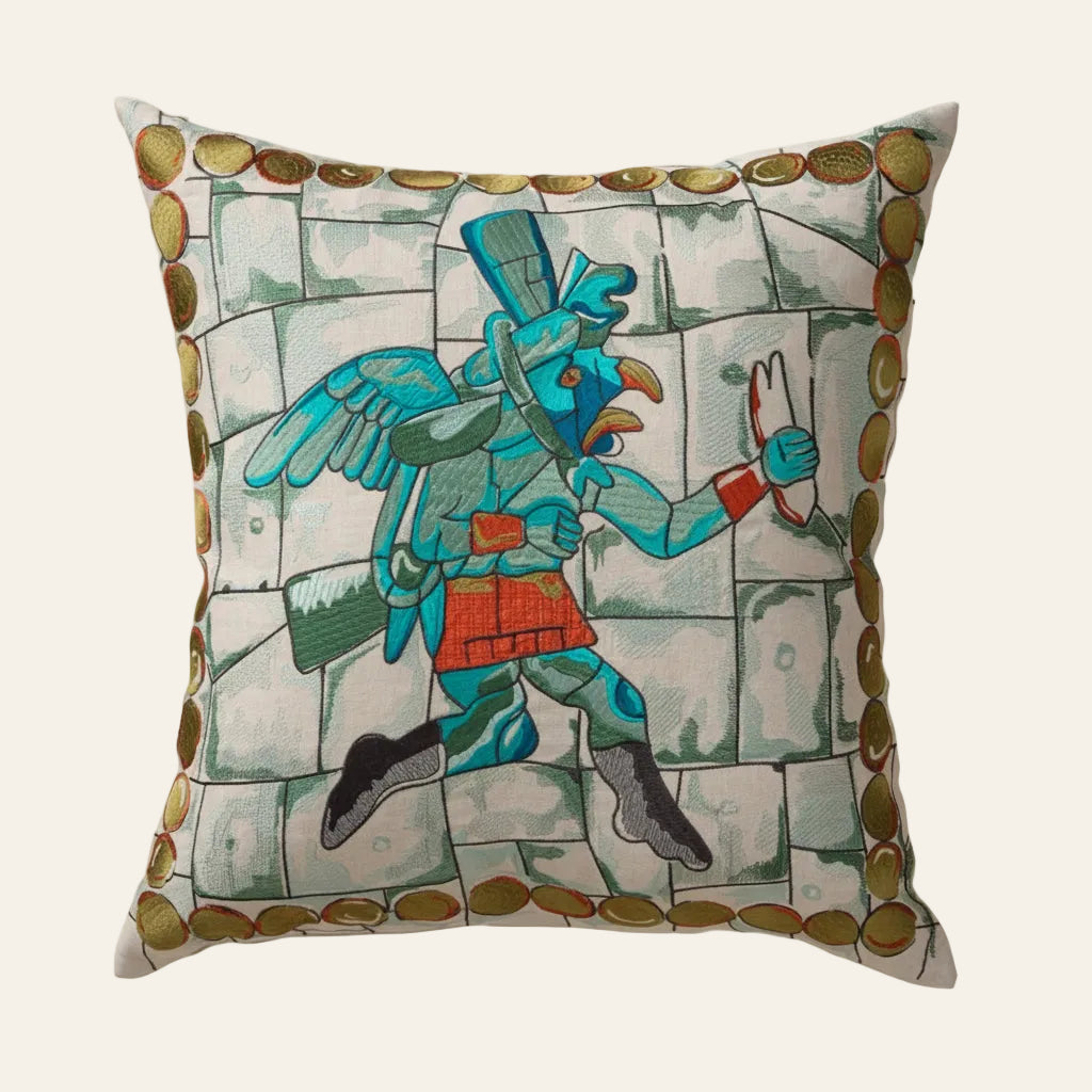 Ann Gish Winged Runner pillow with turquoise Aztec warrior figure on stone-print ground with gold border.
