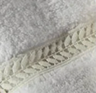 Close-up of ivory cotton terry with woven wreath leaf border detail.