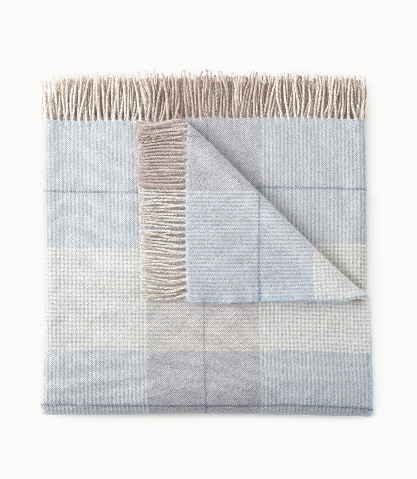Corner fold detail of Peacock Alley York throw revealing plaid pattern in mist and sand with fringe trim.