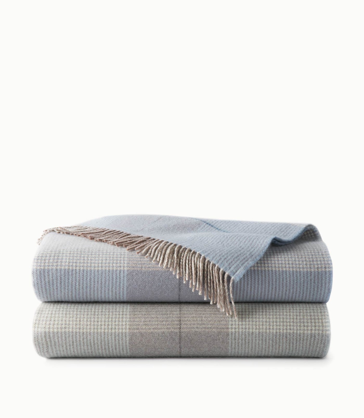Two folded Peacock Alley York throws stacked, plaid pattern in mist blue and stone with fringe detail.