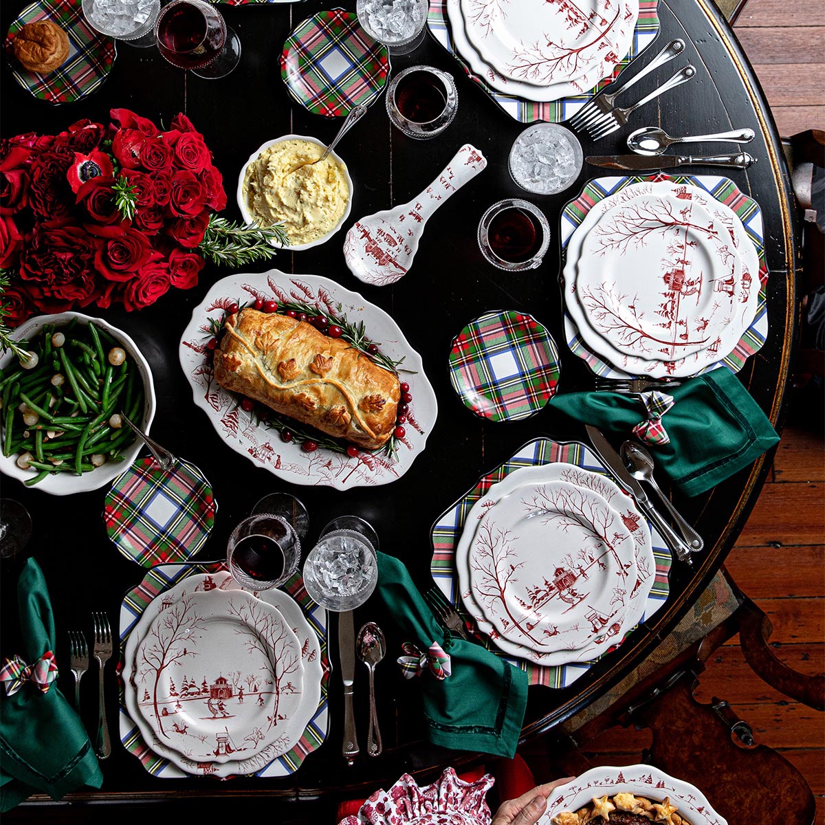 Overhead holiday table set with ruby Winter Frolic plates and a roast