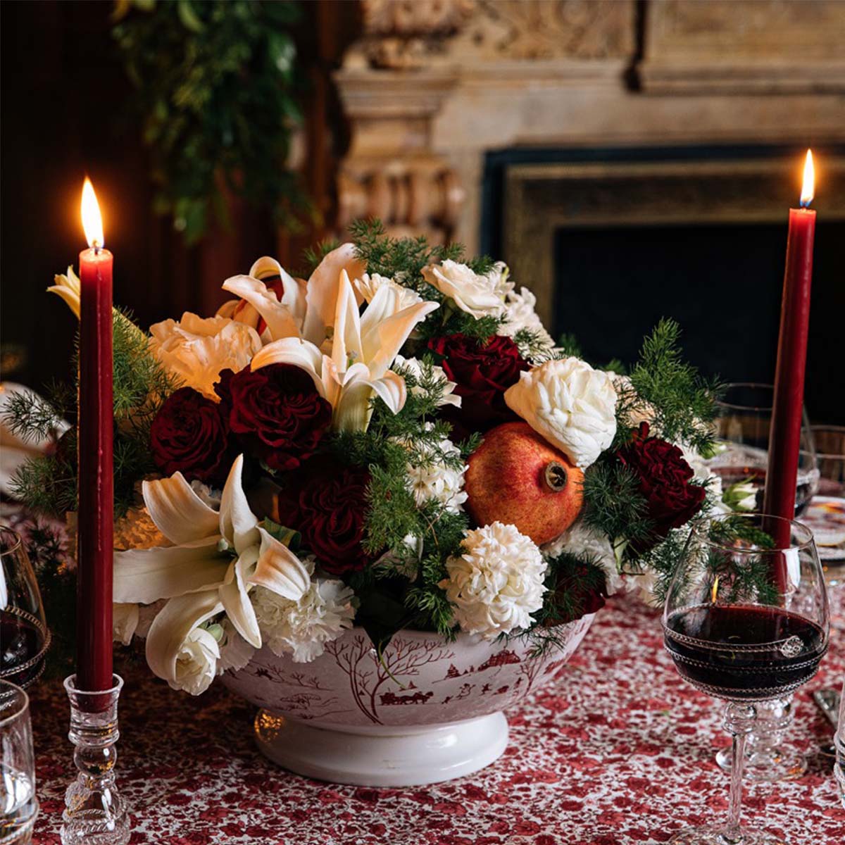 Ruby Winter Frolic centerpiece bowl filled with lilies and red roses between red candles