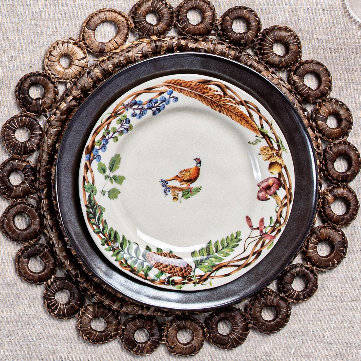 Forest Walk pheasant salad plate on a dark charger inside a brown woven ring placemat